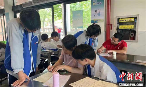 资料图：高考首日，江山市第五中学学生在休息间隙抓紧向老师请教。 